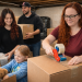 A family packing boxes in a dim basement while getting ready to move to a new home.